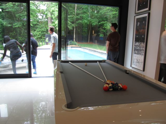 Sleek modern pool table, and view outside to the lap pool.
